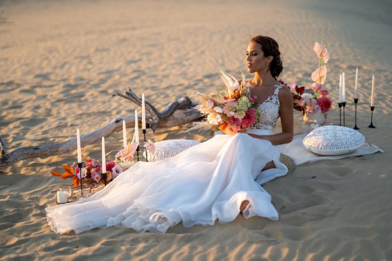 Menyasszony sivatagi környezetben ül a földön dekorációs eszközök között